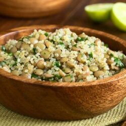 quinoa salad with lentils and parsley in wooden bowl photographed on dark wood with natural light selective focus focus one third into the salad